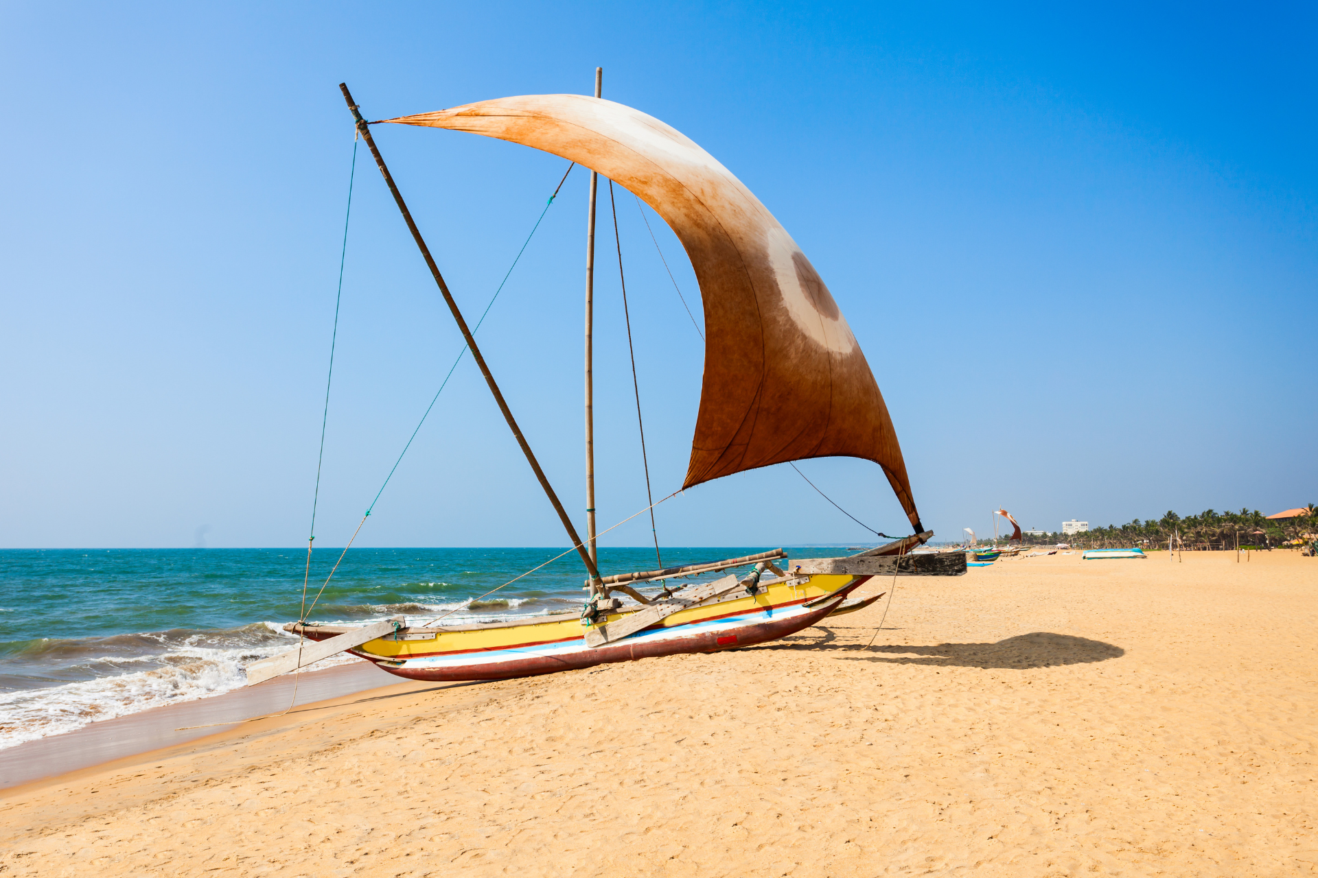 A traditional fishing boat with a sail at the Negombo beach in Sri Lanka